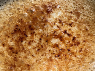 Bubbly texture of a golden-brown creme brulee as it cooks. Surface features a delightful pattern of crispy edges