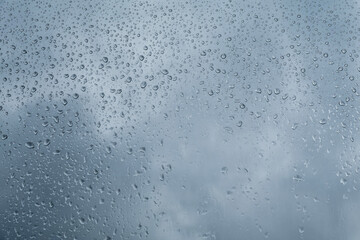 Water Drops On The Pane. Raindrops of Water On The Window Glass. Blue Cloudy Sky in a Background....