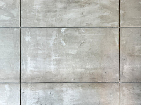 Close up of decorative grey cement concrete wall  in rectangular tiles and grouts. Concrete wall is often used for industrial and raw material suitable for building. Seamless background texture.