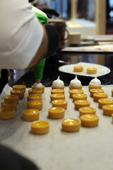 repostero rellenando tartaletas con crema pastelera con una manga pastelera