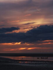 As dusk settles, streaks of warm light linger just above the horizon, breaking through heavy clouds. 