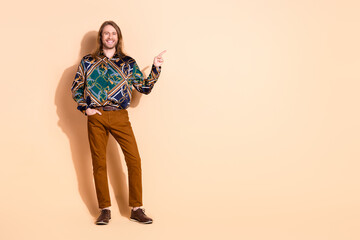 Confident young man in stylish attire pointing with a cheerful attitude on a minimalist beige...