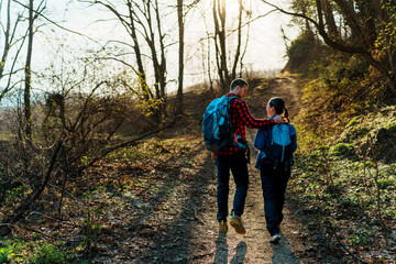 Two hikers with backpacks strolling along a forest path at sunset, soaking in the serene beauty of nature and enjoying moments of tranquility together