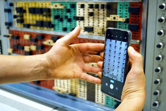 An immersive look at a museum visit: a smartphone in a man's hands, on the screen of which a fragment of a transistorized analog computer from the 1970s is visible. New and outdated technologies