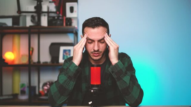 Frustrated Content Creator Sitting at Desk with Hands on Head Struggling with Creative Block