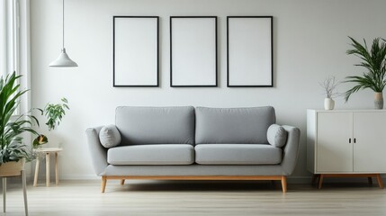 Minimal living room interior with grey couch near white cabinet and wall posters. Genuine photo.
