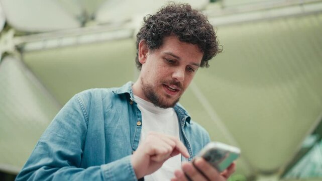 Close-up, man looks at google map on mobile phone and looks around on modern city background