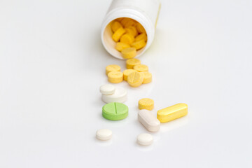 close-up of yellow, green and white pills with medicine bottle background on isolated white background