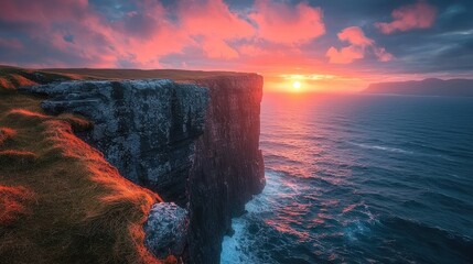 Dramatic sunset over a dramatic cliff face overlooking a turbulent sea.