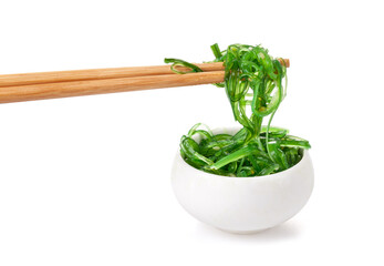 Chopsticks holding Japanese seaweed salad. Japanese cuisine - Wakame salad, Chuka seaweed salad isolated on a white background.
