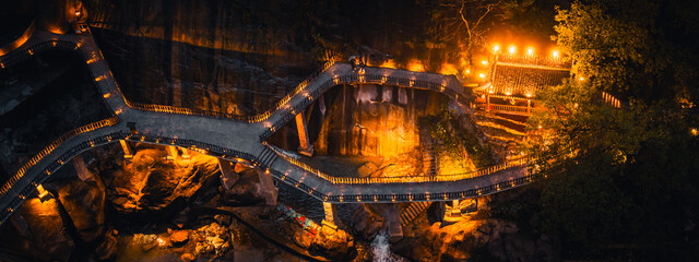 Scenic illuminated pathway winding through Wangxian Valley Town at night, blending natural rock formations and traditional Chinese architecture in a peaceful mountain setting. © Irin