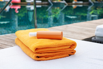 Beach towels and sunscreen on sun lounger near outdoor swimming pool. Luxury resort