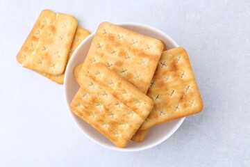 Tasty salty crackers on white table, top view
