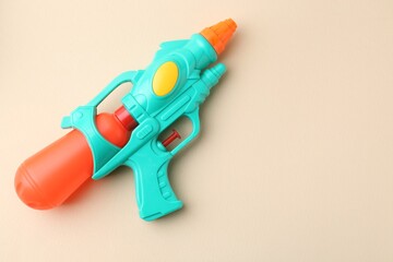 Bright plastic water gun on beige background, top view. Space for text