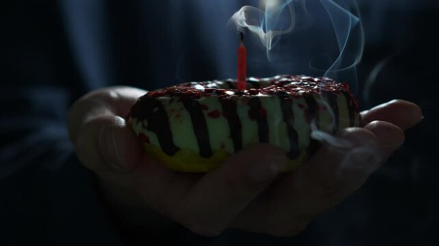 Birthday boy blows out candle on cake on birthday.
Close-up of blowing out candle.
Celebrate birthday.
Putting out candle in donut.
Donut, birthday, holiday, party, fun