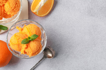 Tasty orange sorbet, fresh fruits and mint on light grey table, flat lay. Space for text