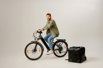 Obraz premium Delivery cyclist posing with bike and insulated bag in studio setting for promotional purposes