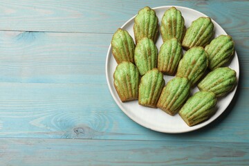 Tasty matcha madeleine cakes on light blue wooden table, top view. Space for text