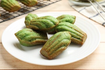 Tasty matcha madeleine cakes on light wooden table, closeup