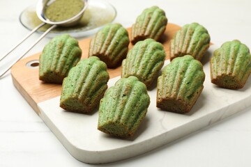 Tasty matcha madeleine cakes on white marble table, closeup
