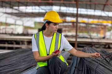 Female construction worker inspecting materials on-site with precision. Safety and expertise in action. Civil engineer or technician checking quality of steel bars for a construction