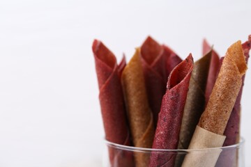 Tasty fruit leather rolls on white background, closeup