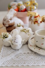 Happy Easter decor on the table in the kitchen. Eggs, Easter cake, sweets, flowers, basket and candles. Easter decoration traditions