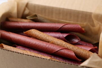 Tasty fruit leather rolls in cardboard box, closeup
