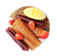 Delicious fruit leather rolls, berries and mango isolated on white, top view