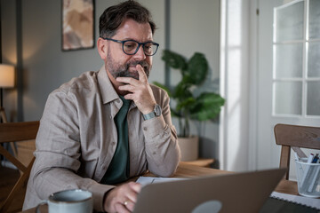 Naklejka premium Focused entrepreneur working from home office using laptop