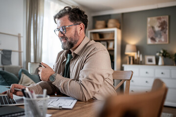 Architect enjoying coffee while working from home on laptop