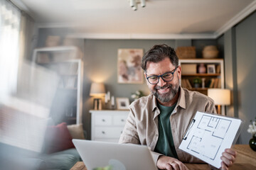 Architect showing blueprint on video call from home office