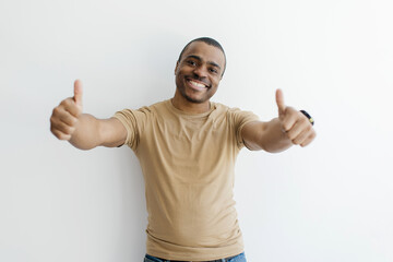 Fototapeta premium Cheerful Black Man Showing Thumbs Up At Camera With Two Hands, Happy Excited African American Male Gesturing Sign Of Approval While Standing Over White Studio Background, Copy Space
