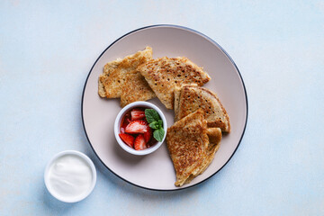 Sweet rye and whole grain crepes with strawberry and sour cream directly above