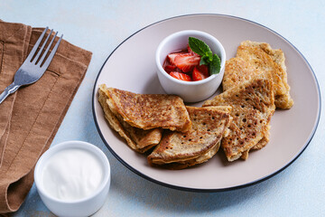 Sweet rye and whole grain crepes with strawberry and sour cream directly above