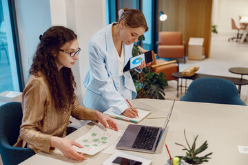 In a modern office setting, two skilled professionals are engaging in dynamic and creative...