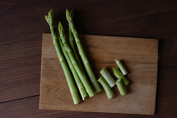 cutting Green Asparagus on wooden cutting board table