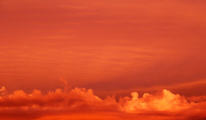 Sky with clouds illuminated by orange lights at sunset