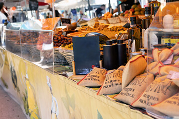 Market stall with fresh vegetables and fruit as well as bags with the imprint Herbs of Provence in Port Grimaud