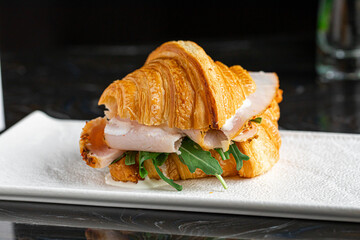 Portion of gourmet croissant sandwich with turkey and arugula
