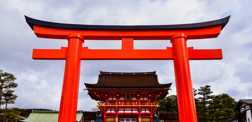 Torii gate, a traditional Japanese gate, serves as entrance to Shinto shrine in background - Kyoto, Japan