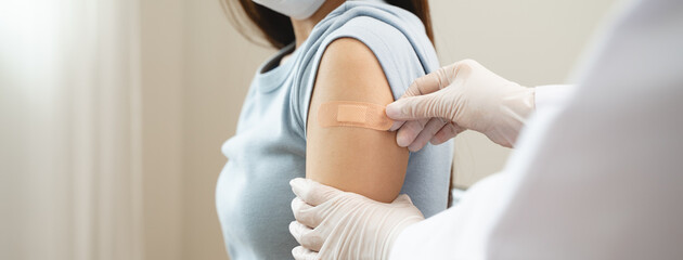 People getting a vaccination to prevent pandemic concept. Woman in medical face mask  receiving a dose of immunization coronavirus vaccine from a nurse at the medical center hospital