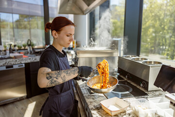 A skilled chef tosses freshly made pasta in a bright kitchen filled with natural light, creating an energetic vibe