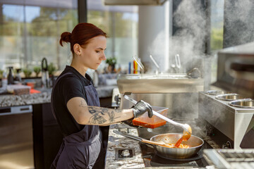 A highly skilled chef gracefully stirs a steaming pot full of flavorful and aromatic sauce in a modern kitchen