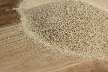Dry yeast scattered on wooden surface, copy place for text.