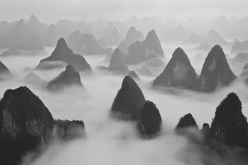 Misty mountain range in monochrome, showcasing numerous peaks shrouded in fog.