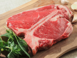 Luxurious T bone steak on a wooden cutting board with garlic and