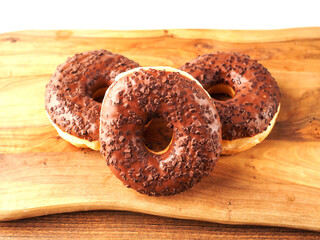 Sweet tasty chocolate donuts on wooden board. Popular desert and snack. Fine bakery product.