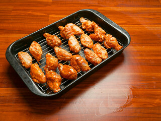 Cooking fresh chicken wings on an oven. The product is covered in red Asian style sauce and ready for cooking in high temperature. Party finger snack food.