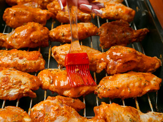 Cooking fresh chicken wings on an oven. The product is covered in red Asian style sauce and ready for cooking in high temperature. Party finger snack food.